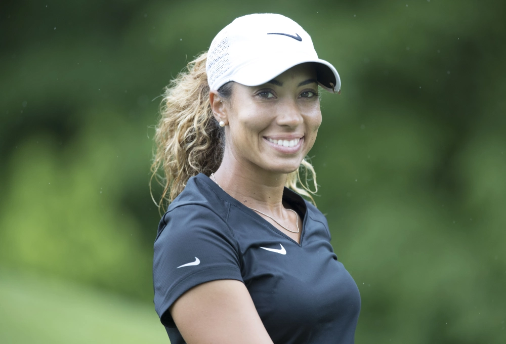 A Royce Renee Woods Nike sports cap and shirt, standing outdoors with a blurred green background.