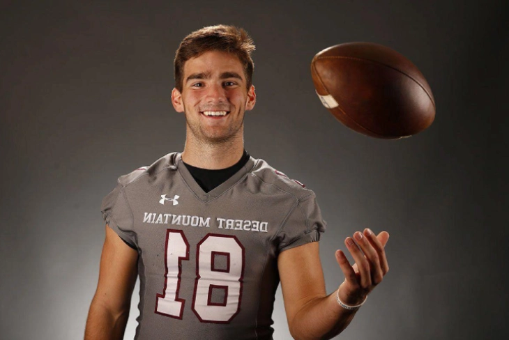 Kade Eugene Warner in a Desert Mountain football jersey tossing a football mid-air.