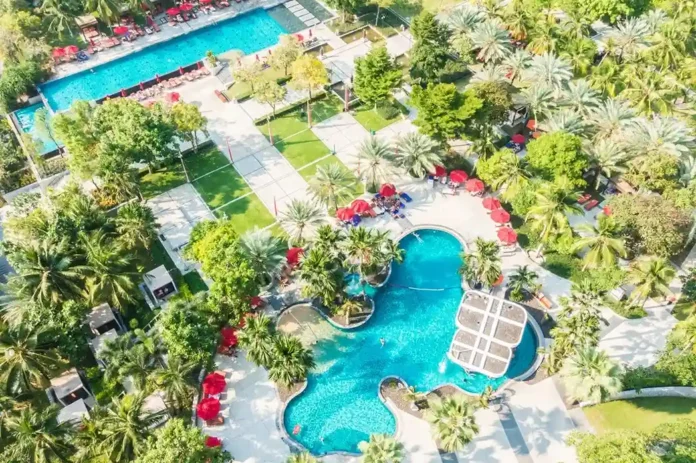 Aerial view of luxury Palm Springs hotel with outdoor pool, palm trees, and relaxing seating areas under sunny skies.