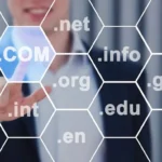 A person in a business suit pointing to a digital display of various domain extensions like .com, .net, .org, .gov, .edu, .info, and others.