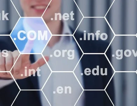 A person in a business suit pointing to a digital display of various domain extensions like .com, .net, .org, .gov, .edu, .info, and others.