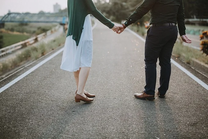 Couple holding hands on a pathway, viewed from behind