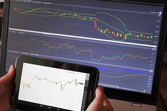 Forex trading charts displayed on a tablet and computer screen