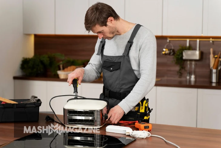 Technician performing appliance repair on a refrigerator, demonstrating essential home maintenance skills