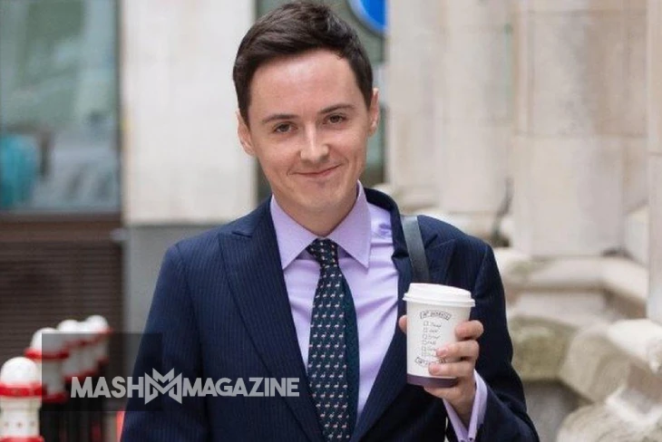 Darren Grimes, a young British political activist, speaks at a podium with a serious expression.