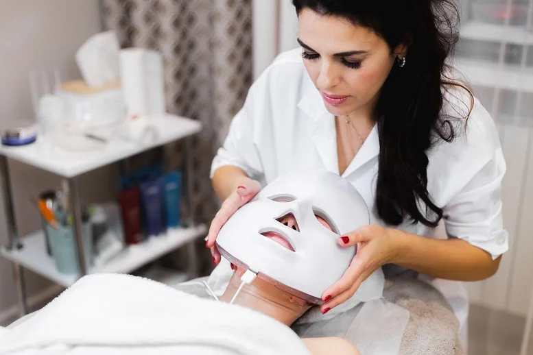 Beauty expert applying a light therapy mask for skin treatment