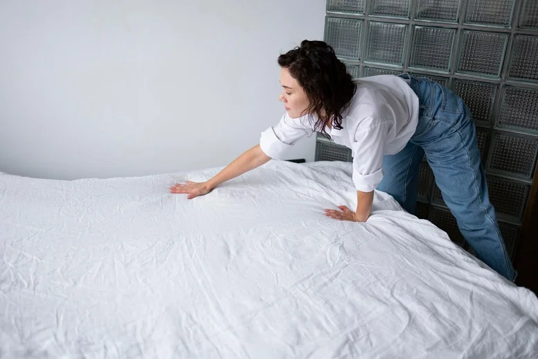 Woman inspecting a freshly made bed to test the comfort of a mattress