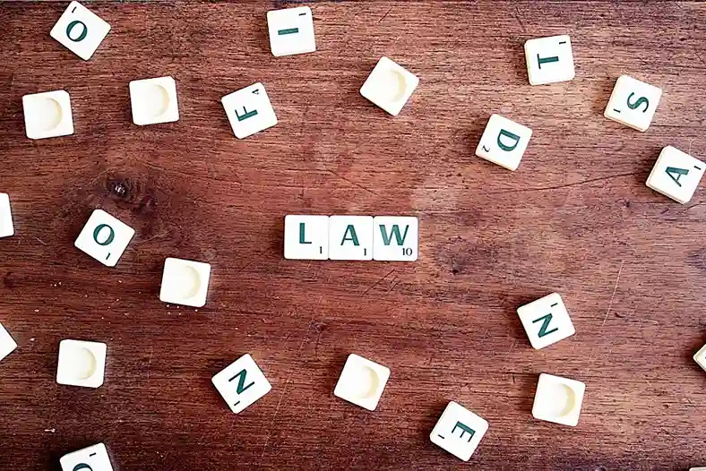 A wooden surface with scattered letter tiles spelling "LAW," symbolizing legal knowledge and the importance of staying informed in a criminal case.