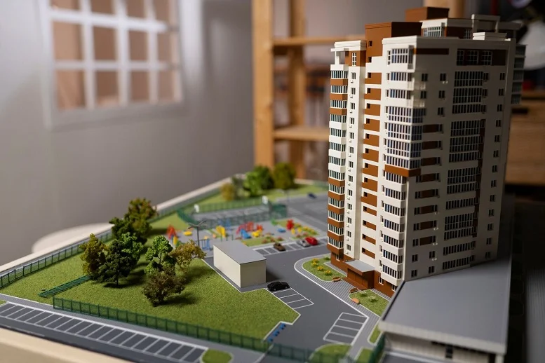 Property development model featuring a high-rise building and planned community amenities like parks and parking spaces.