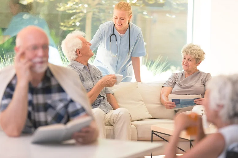 Senior Assistance Programs: Smiling caregiver in a nursing home assisting senior residents during a group activity.