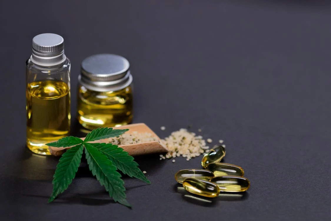 Marijuana edibles with hemp leaves and CBD capsules on a dark background, representing cannabis components and their effects.