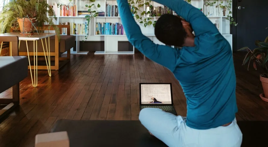 A man practicing yoga in a cozy living room, symbolizing a holistic approach to well-being with mindfulness and health tracking.