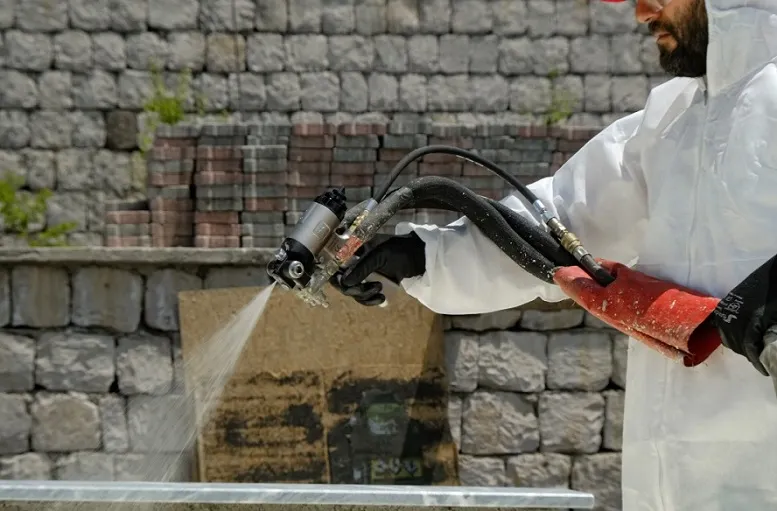 A worker in a white coverall applying spray foam insulation for superior air sealing and moisture resistance.